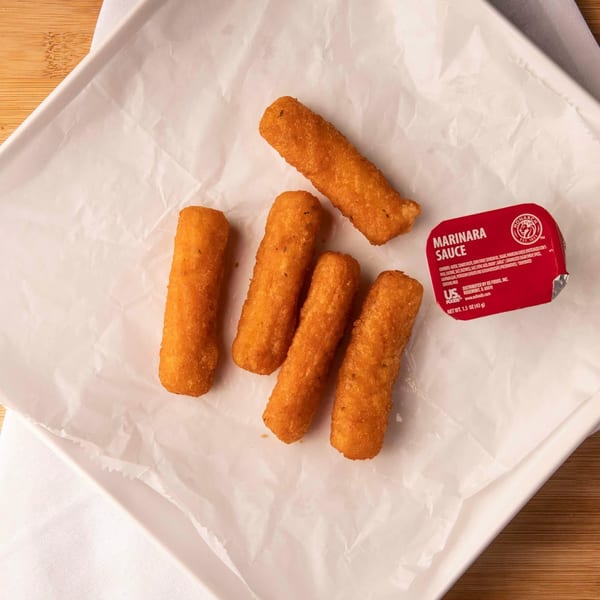 Five golden-brown mozzarella sticks and a red marinara sauce cup on white paper.